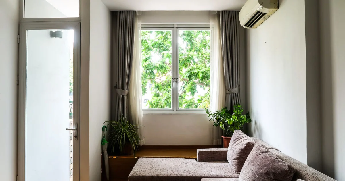 Salón con un aire acondicionado de pared junto a una ventana y plantas
